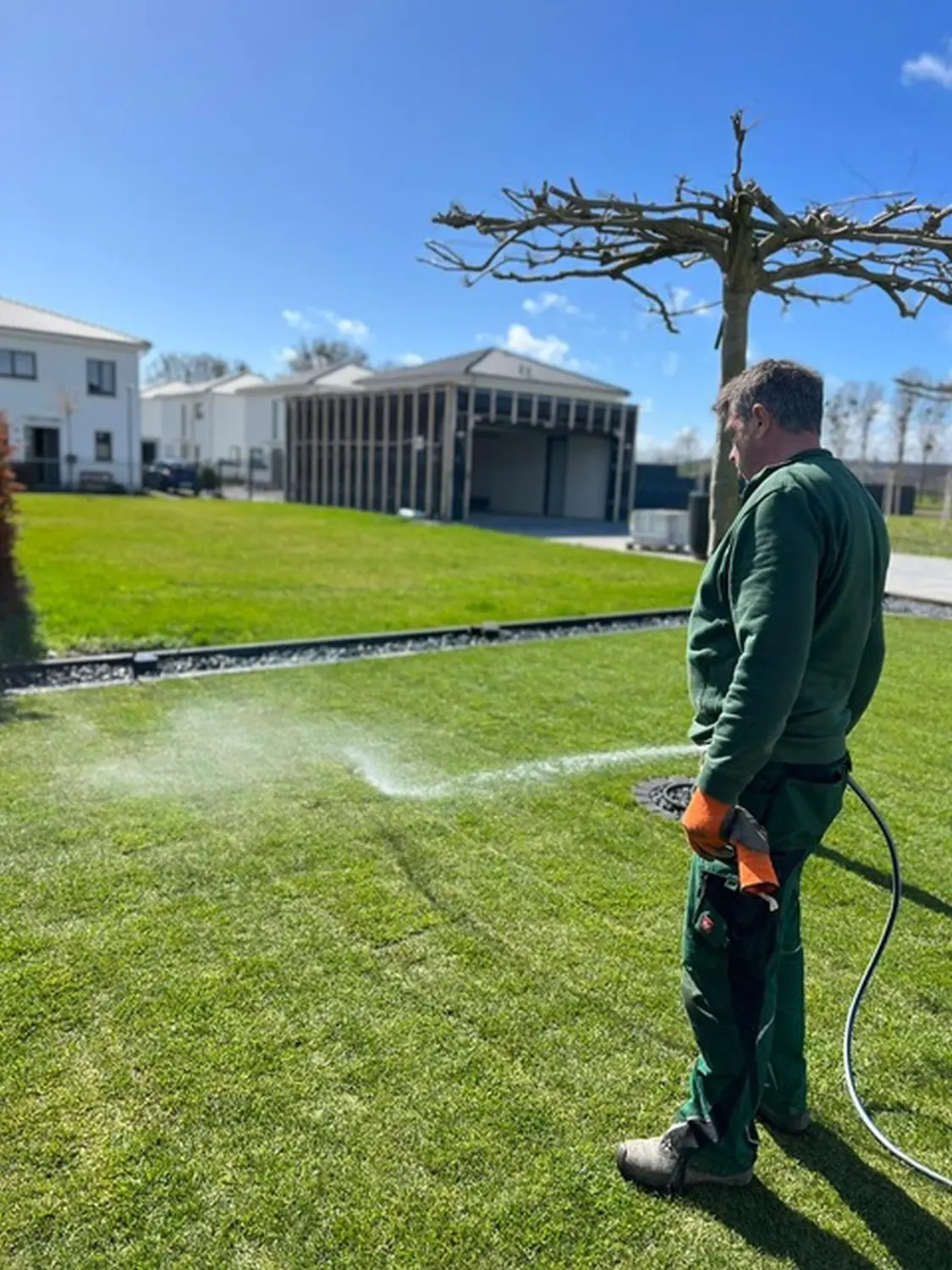 Mein Gärtner Bonn Mann gibt Wasser ins Gras